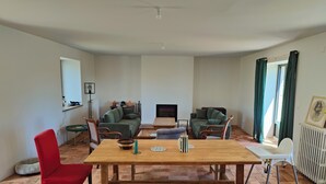 Ein Wohnzimmer mit einem Holztisch, roten und grünen Stühlen, einem Kamin und einer Heizung.