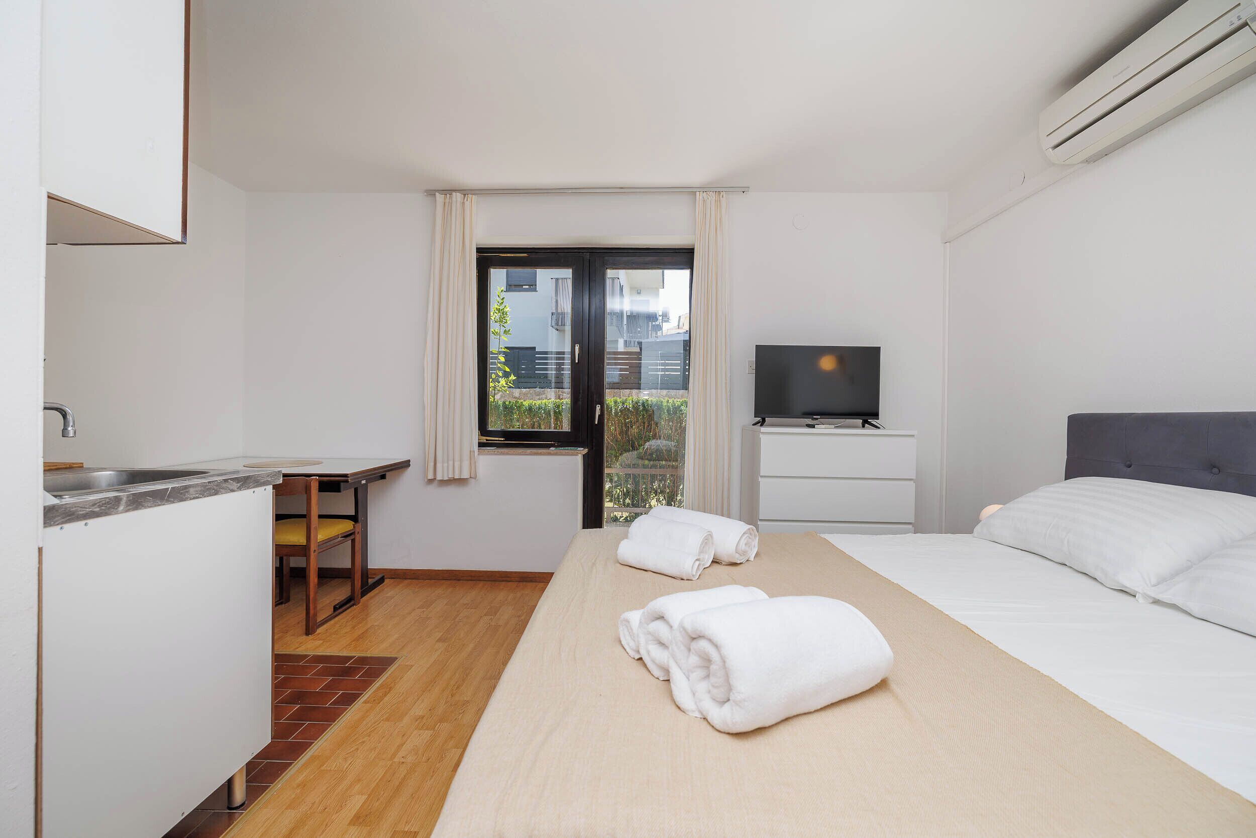 Habitación de hotel con cama, televisión, escritorio y ventana.
