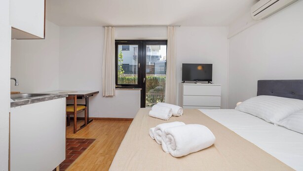 Ein Hotelzimmer mit Bett, Fernseher, Schreibtisch und Fenster.