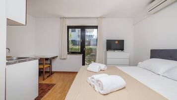 Habitación de hotel con cama, televisión, escritorio y ventana.