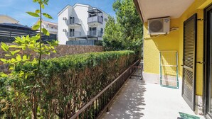 Ein Balkon mit Metallgeländer, einer gelben Wand und einer Steinwand im Hintergrund.