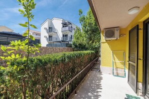 Ein Balkon mit Metallgeländer, einer gelben Wand und einer Steinwand im Hintergrund.
