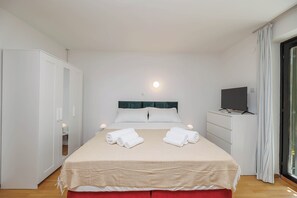 Ein Hotelzimmer mit einem Bett, einem Fernseher, einem Kleiderschrank und einem Fenster mit Vorhängen.