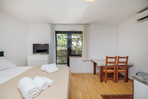 Una camera d'albergo con un letto, una scrivania con una sedia, una televisione e una finestra con tende.