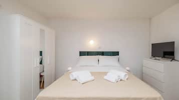 A hotel room with a bed, a television, a wardrobe, and a desk.