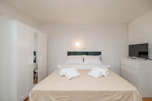Ein Hotelzimmer mit einem Bett, einem Fernseher, einem Kleiderschrank und einem Schreibtisch.