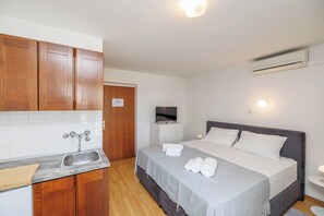 Ein Schlafzimmer mit Bett, Nachttisch und einem an der Wand befestigten Fernseher.