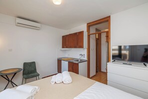 Ein Hotelzimmer mit einem Bett, einer kleinen Küchenzeile, einem Sessel und einem Fernseher.