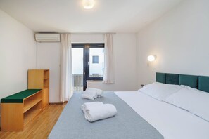 Et hotelværelse med en seng, en træbænk, et vindue med gardiner og udsigt ud