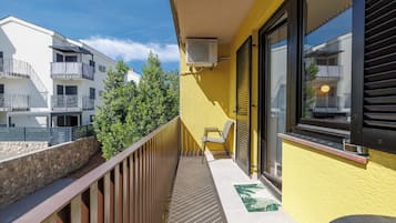 Parvekkeella on tuoli, ikkunassa on sälekaihtimet ja huoneessa on ilmastointilaite.