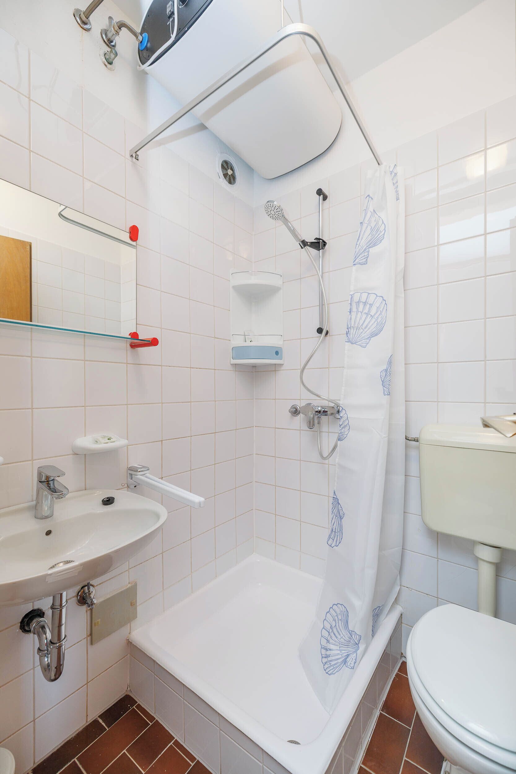 Un baño con cabina de ducha, lavabo, inodoro y espejo.