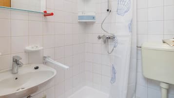 Un baño con cabina de ducha, lavabo, inodoro y espejo.