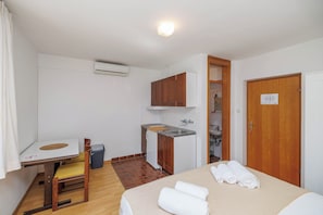 A compact hotel room with a bed, a small desk, a chair, a sink, and a wardrobe. - Charming Studio Retreat in Malinska-Dubašnica with Garden View (Malinska-Dubašnica)