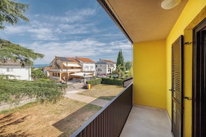 A balcony with a yellow wall and a view of a residential area with houses and a clear sky. - Moder studio for 2 persons in Malinska, island of Krk (Malinska-Dubašnica)