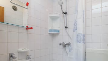 Kylpyhuone, jossa on valkoinen pesuallas, kylpyamme, wc ja suihku, jossa on suihkuverho.
