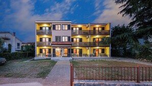 A multi-story hotel with balconies, a well-lit entrance, and a clear night sky. - Charming Studio for 4 persons in Malinska (Malinska-Dubašnica)