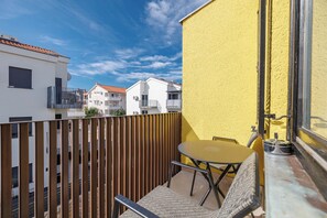 A balcony with a table and chairs, a wooden fence, and a yellow wall. - Charming Studio for 4 persons in Malinska (Malinska-Dubašnica)