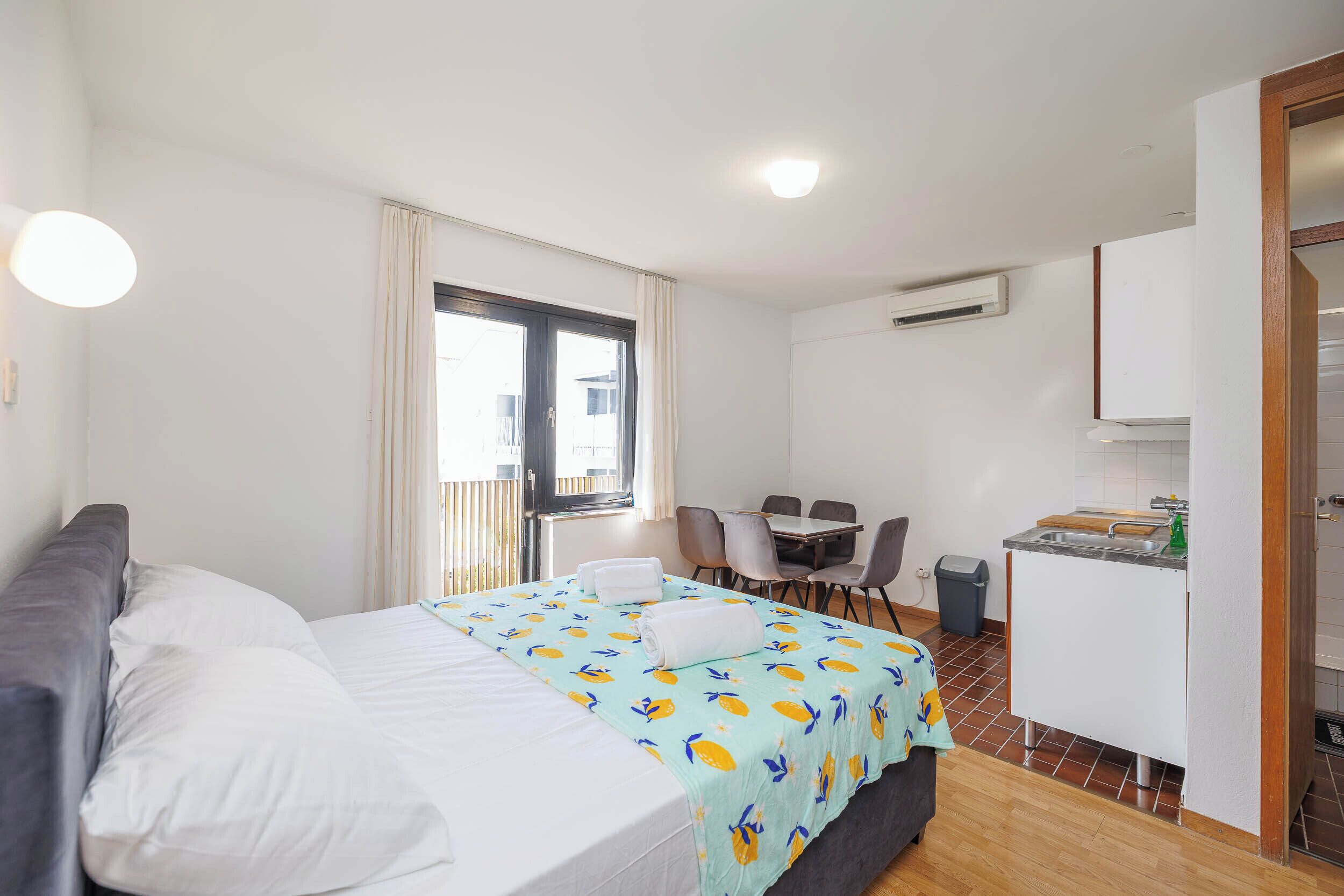 Un dormitorio con cama, escritorio y kitchenette.
