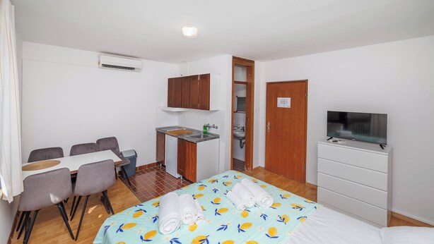 Une chambre d’hôtel compacte comprenant un lit, une télévision, une petite kitchenette et un coin repas.