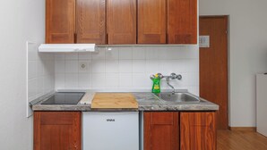 Une cuisine avec des meubles en bois, un lave-vaisselle blanc, un plan de travail en granit et un évier en acier inoxydable.