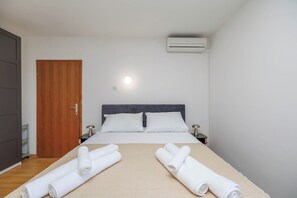 A hotel room with a bed, two bedside tables, a wooden door, and an air conditioning unit. - Charming Studio for 4 personst in Malinska with sea view (Malinska-Dubašnica)