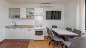 Una cocina compacta con estufa, horno y un comedor con mesa y sillas.