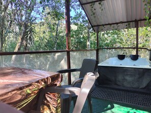 Un espace extérieur abrité, avec une table et des chaises, entouré d’arbres.