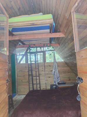 Un intérieur en bois avec un lit, une échelle et une petite table.