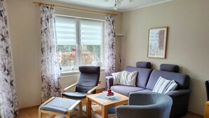 A living room with a sofa, two armchairs, a coffee table, and a window with curtains. - 5 - Schröder Apartment - Comfortable vacation rental in Zingst with a terrace and garden (Zingst)