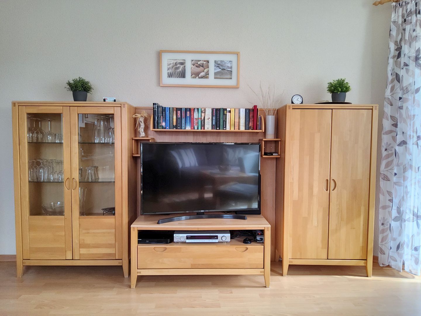 Una sala de estar con televisor, armarios de madera y una estantería.