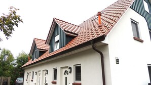 A two-story building with a red-tiled roof, white exterior walls, and a small front porch. - 5 - Schröder Apartment - Comfortable vacation rental in Zingst with a terrace and garden (Zingst)