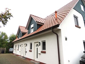 Ein zweistöckiges Gebäude mit roten Ziegeln, weißen Außenwänden und einer kleinen Veranda.