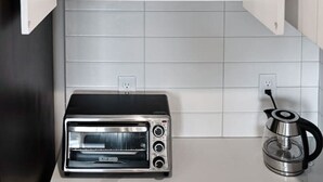 Uma cozinha com forno embutido, chaleira e armário com prateleiras.