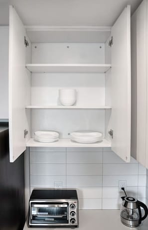 Eine Küche mit Einbauofen, Wasserkocher und einem Schrank mit Regalen.