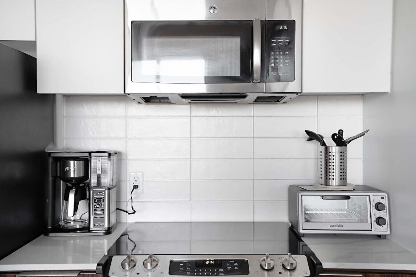 A kitchen with a microwave, coffee maker, toaster, and stove.