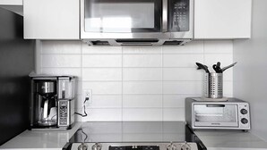 Uma cozinha equipada com micro-ondas, cafeteira, torradeira e fogão.