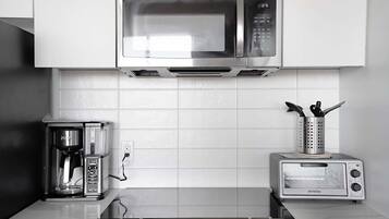 A kitchen with a microwave, coffee maker, toaster, and stove.