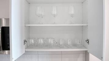 A kitchen with a built-in cabinet, a coffee maker, and a trash bin.