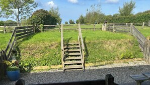 A wooden bench in a garden with a wooden fence, gravel path, and greenery. - Granary @ Ivyleaf Barton, 3 bedroom cottage overlooking golf course to the sea (Bude)