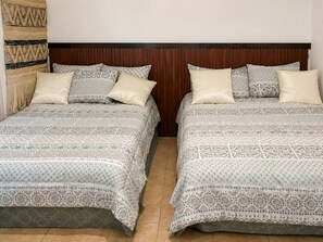 Two beds with patterned bedding, a wooden headboard, and a woven wall hanging. - Los Flamboyanes Cozy Suite (Aguadilla city)