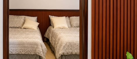 A hotel room with two beds, a ceiling fan, and a potted plant.
