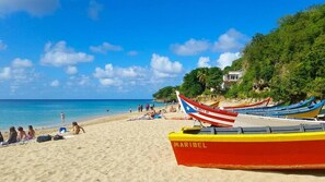A beach with boats, a sandy shore, and a building in the background. - Los Flamboyanes Cozy Suite (Aguadilla city)