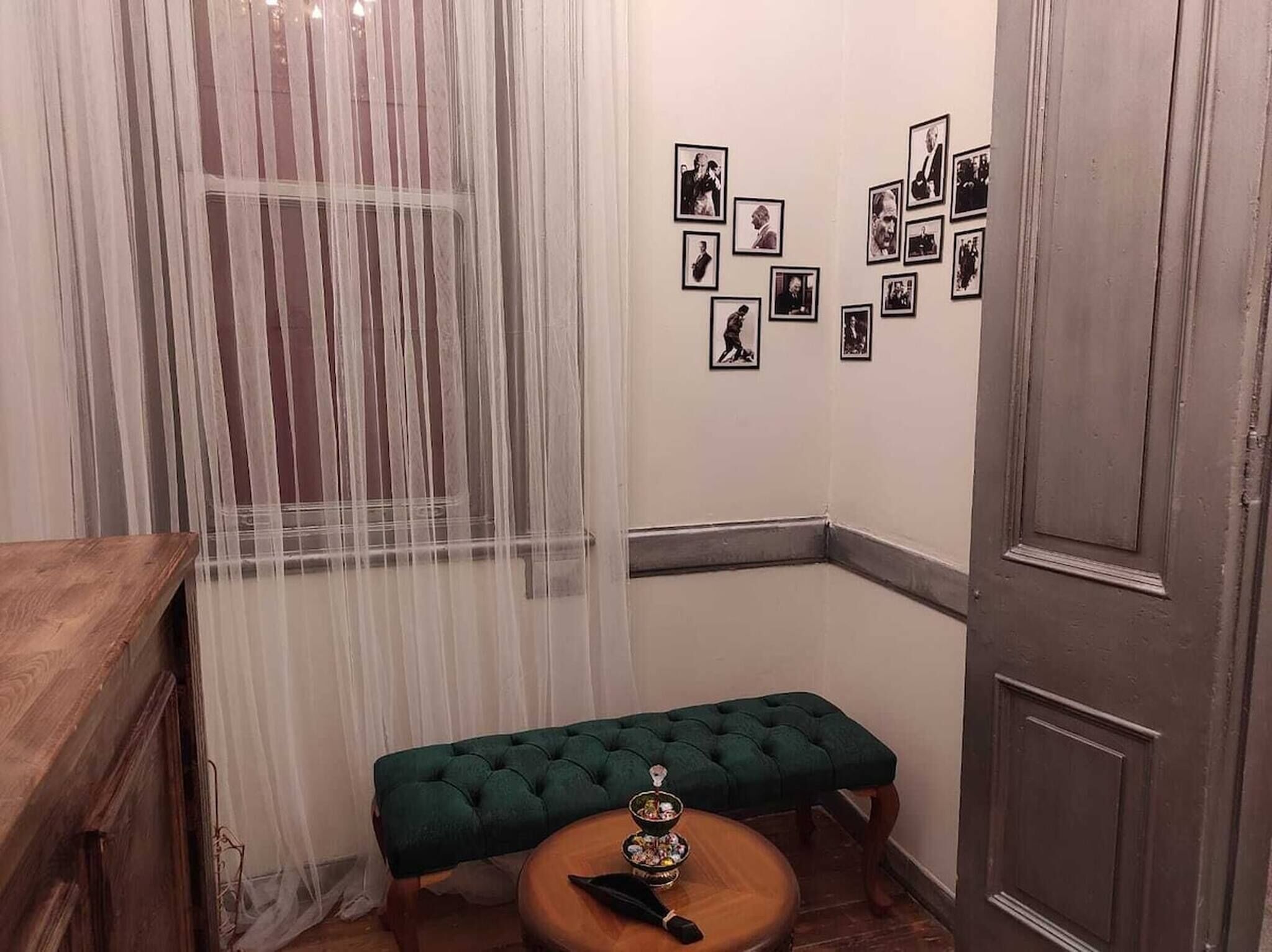 Ein Zimmer mit einer Holzbk, einem kleinen Rundtisch und einer Tür.