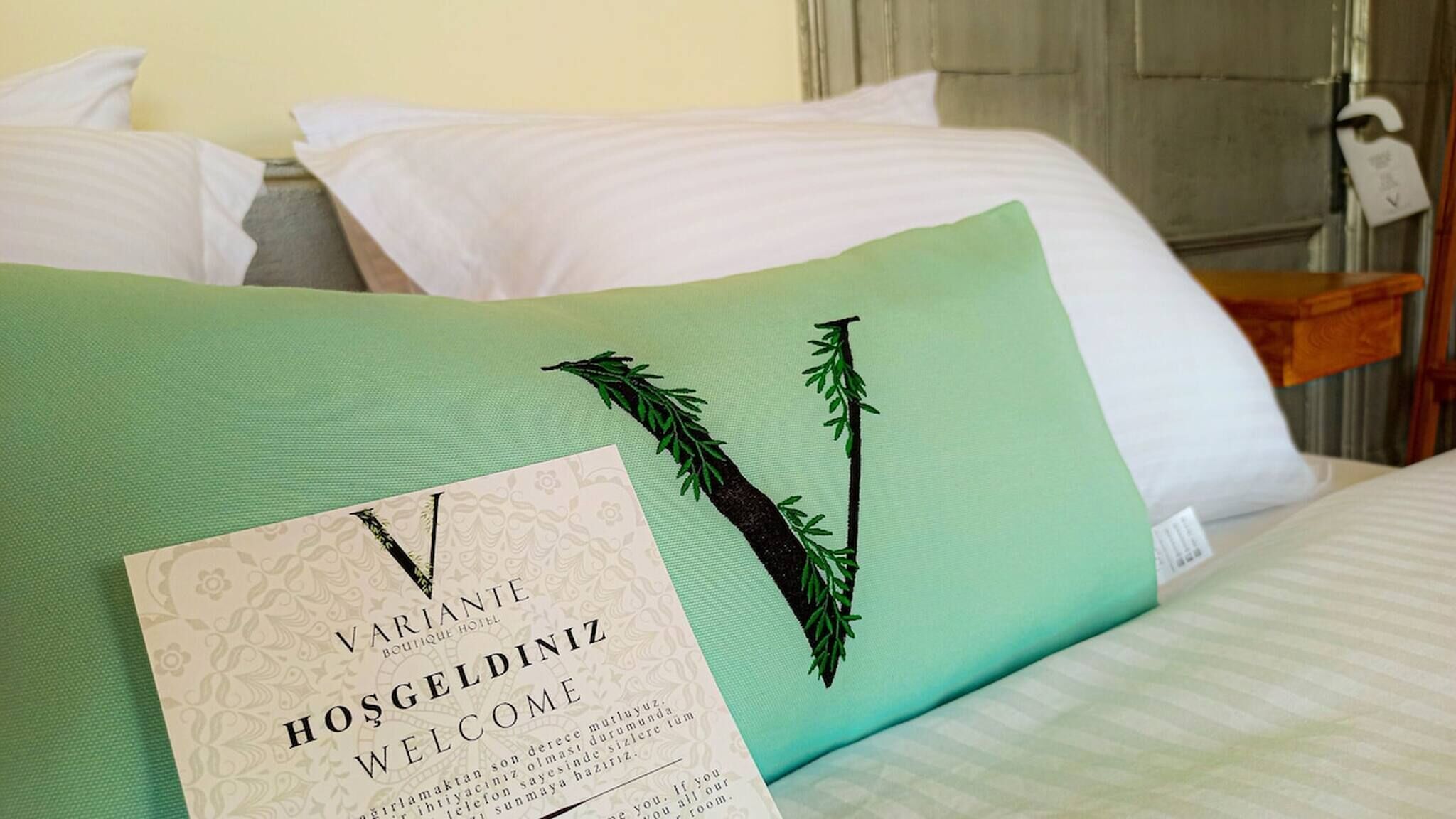 Ein Hotelzimmer mit einem Bett, Kissen und einer Willkommenskarte.