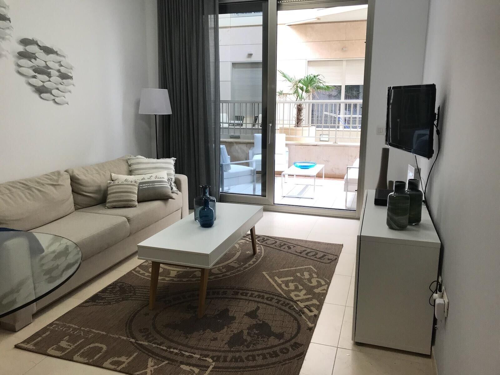 Una sala de estar con sofá, mesa de centro, televisor y vistas al balcón exterior.