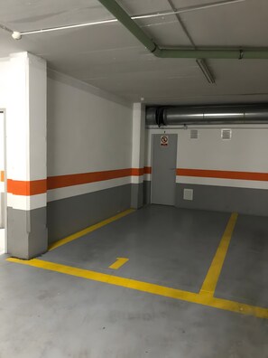 A parking garage with marked parking spaces, a no-smoking sign, and ventilation ducts on the ceiling. - Seafront playa Patacona Mare Nostrum (Alboraya)