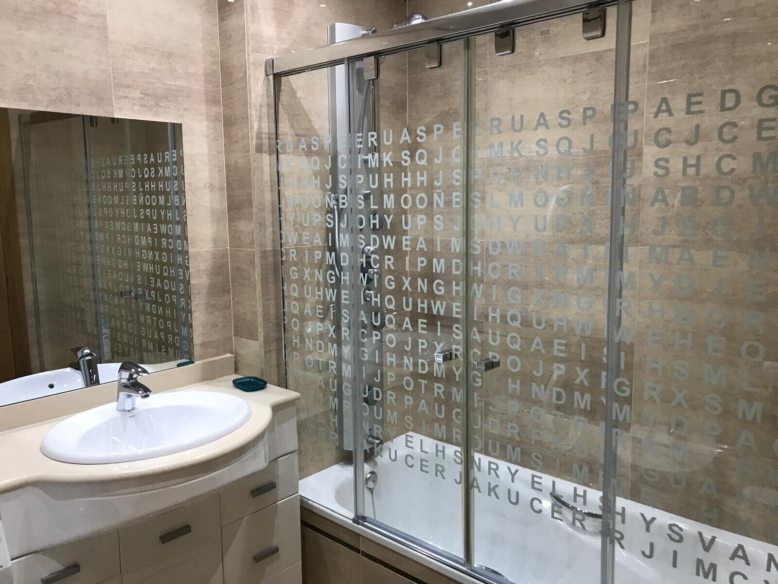 Un baño moderno con cabina de ducha de vidrio, un lavabo con espejo y un mueble de tocador con cajones.