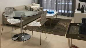 A modern living room with a glass dining table, a sofa, a TV, and a large window with curtains. - Seafront playa Patacona Mare Nostrum (Alboraya)