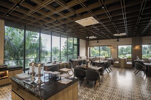 A restaurant with a modern interior, large windows, and a patterned floor. - juSTa Nature's Nest Resort (Rishikesh)