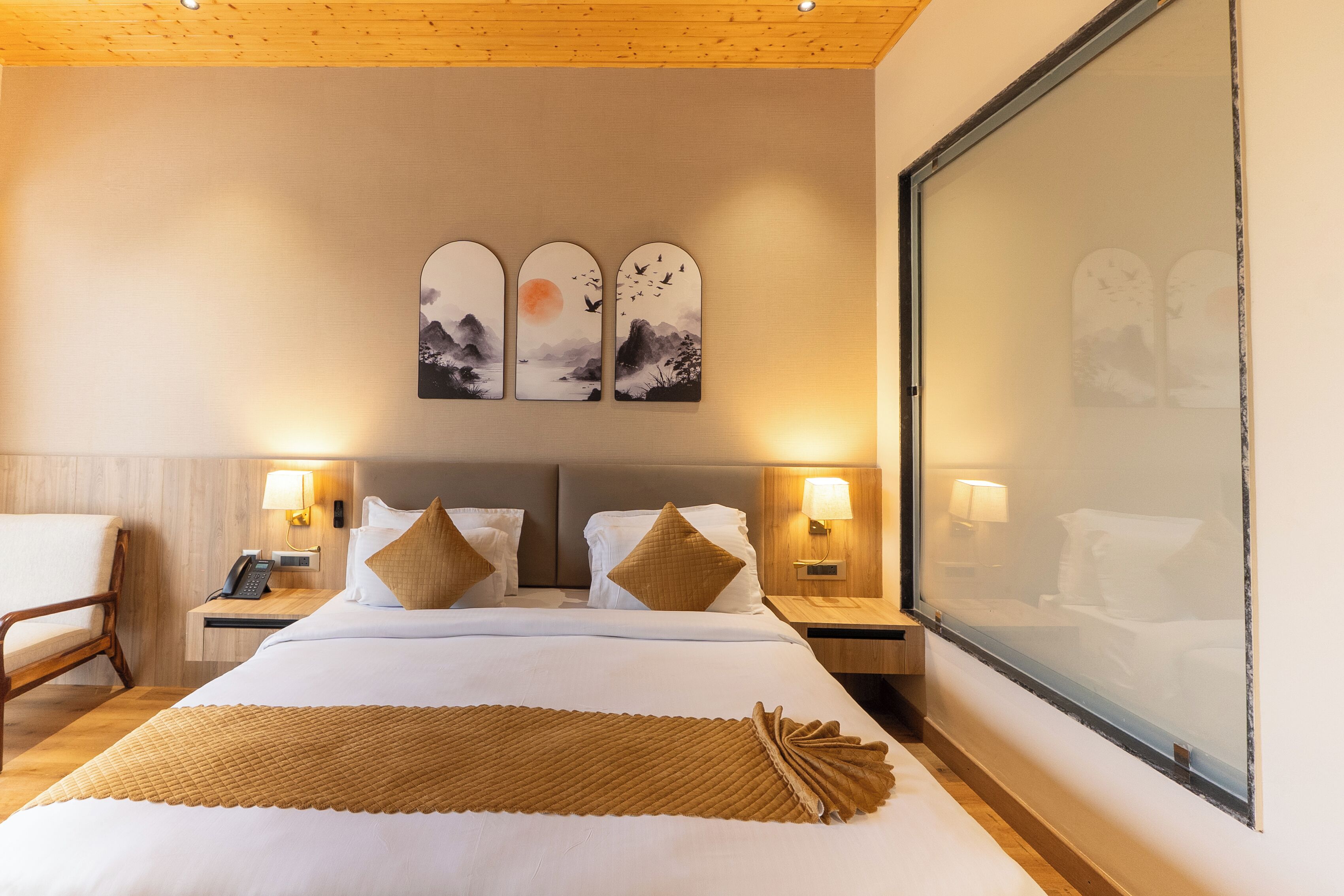 A hotel room with a bed, two bedside tables, a chair, and a large window.